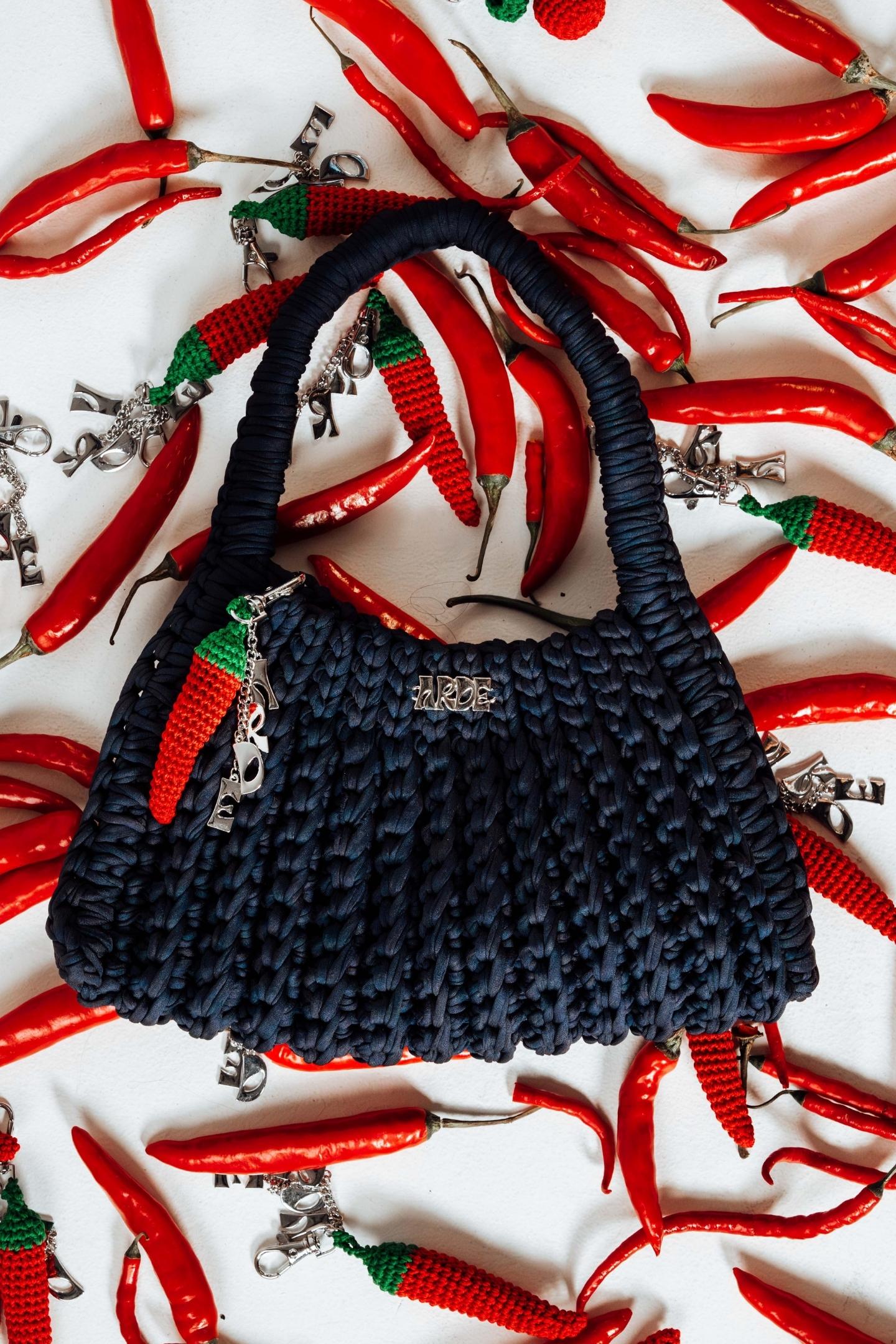 Navy textured handbag with red chili pepper decorations on a white background with red chili peppers bag charms